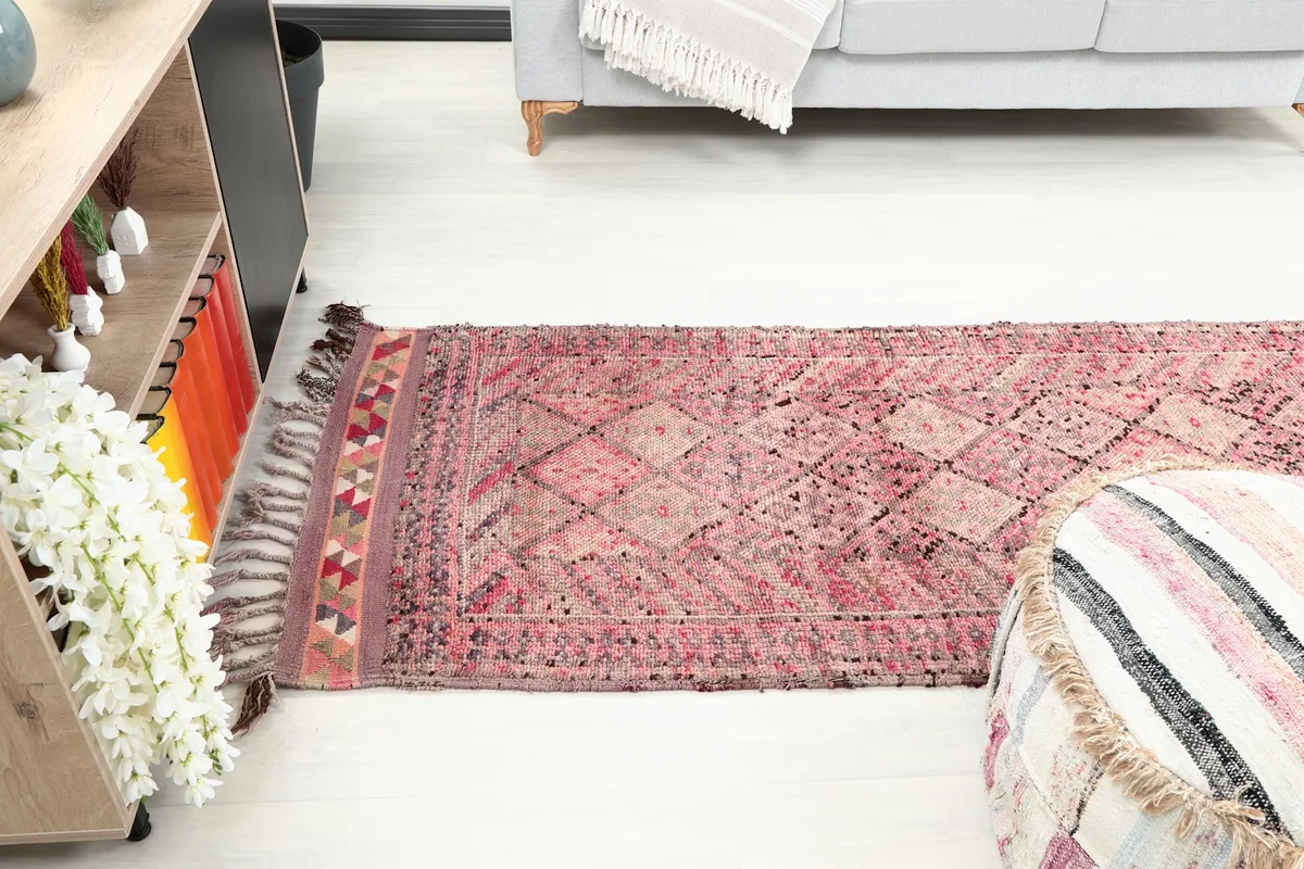 Vintage runner rug extending into a room, with a pouf in the foreground