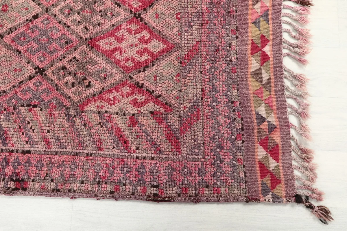 Detail shot of the rug's end, showing geometric patterns, border, and fringes
