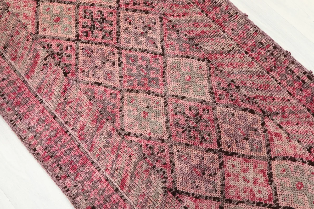 Close-up of the rug's surface, highlighting the various shades of rose, gray, and charcoal in the diamond design