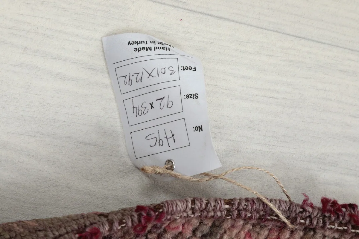 Tag displaying the rug's dimensions in feet and centimeters, and origin