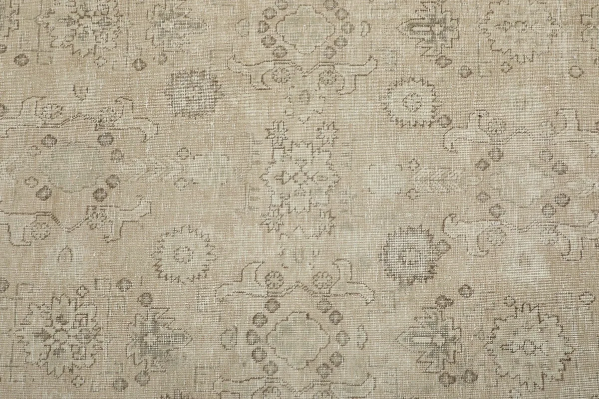 Close-up of the beige rug's field, highlighting scattered gray floral and geometric motifs