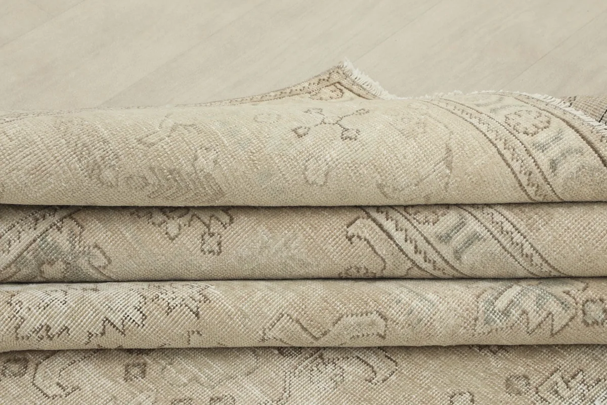 Stacked folds of the beige rug, emphasizing its thickness and woven texture