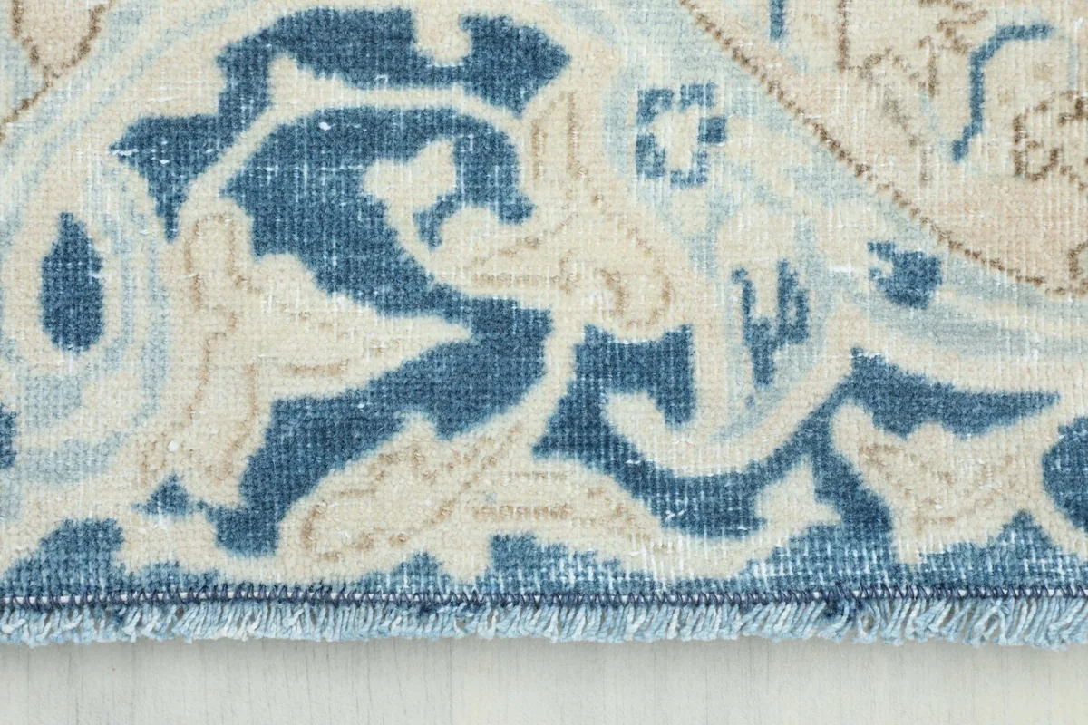 Close-up view of the rich blue border with floral details and fringe.