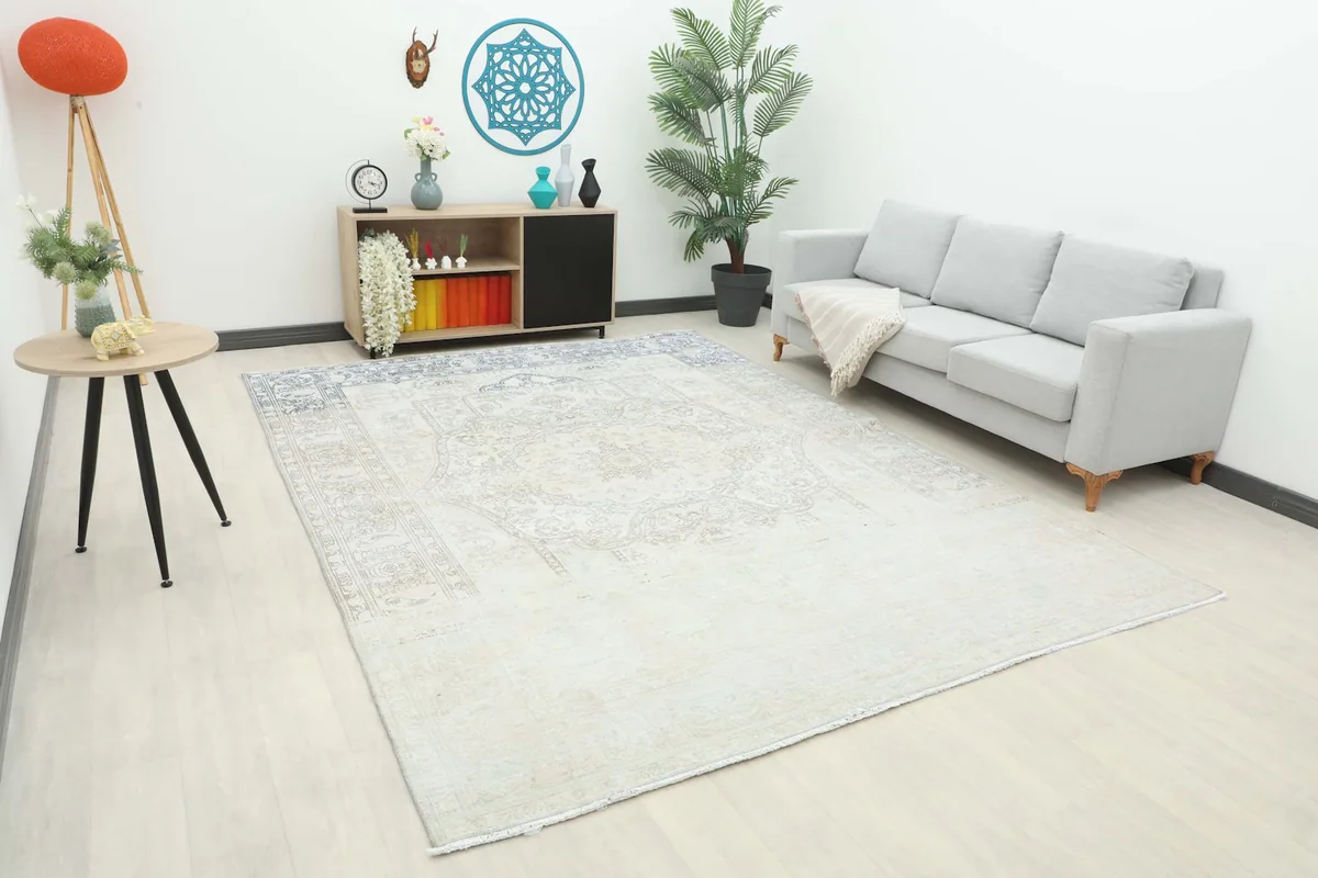 Large 8x11 ivory and gray Persian rug displayed in a living room setting with a light gray sofa