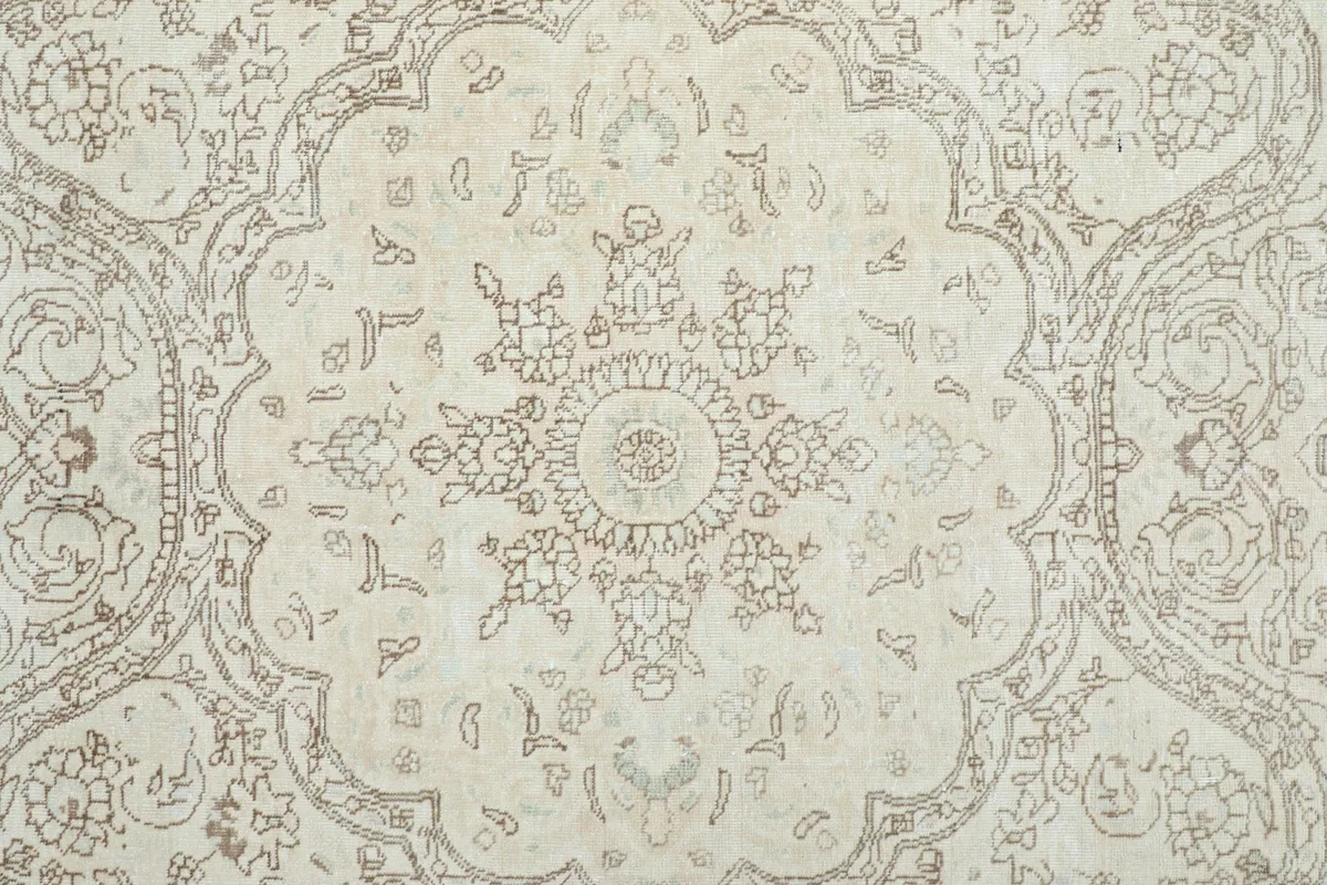 Detail view of the central medallion and surrounding floral patterns in gray on an ivory field
