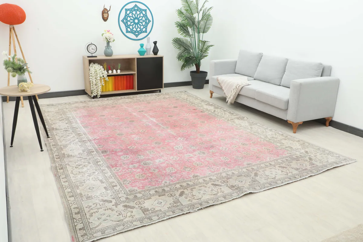 Oversized Faded Rose Geometric Persian Rug in a living room setting with a gray sofa and modern decor.