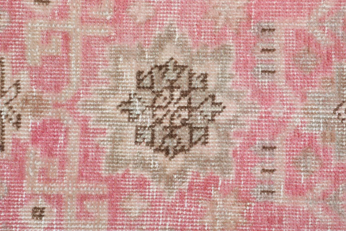 Detailed view of the low wool pile and intricate knotting of a small motif in the faded rose field.