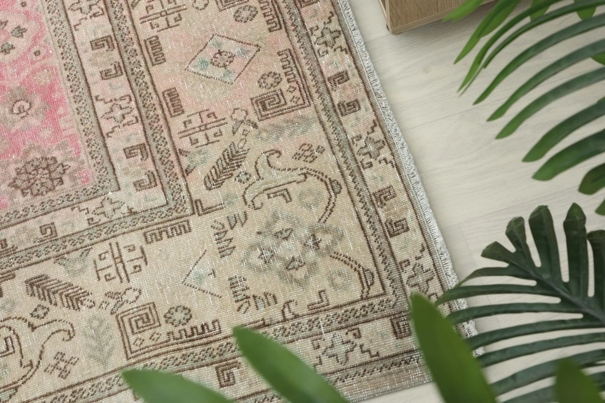 Close-up of a corner of the rug's border, displaying detailed geometric and stylized tribal patterns in beige and gray.