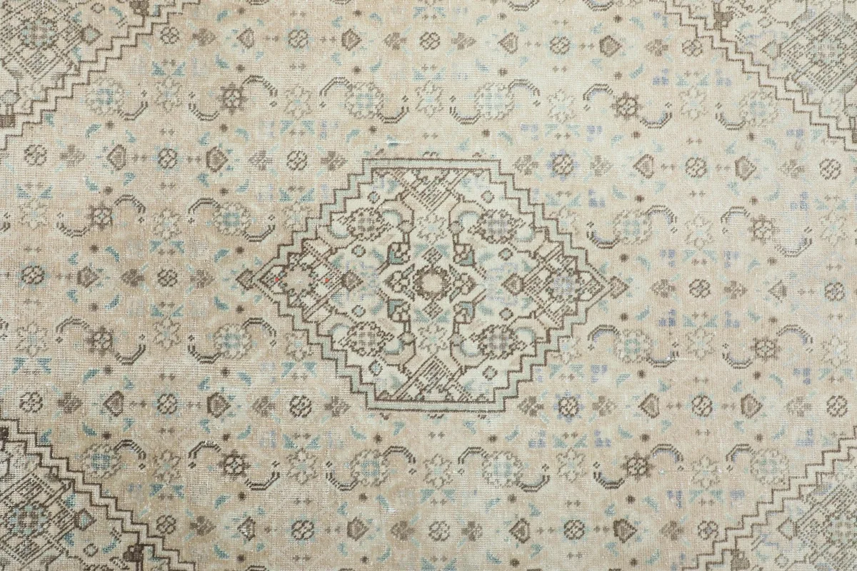 Detailed view of the central medallion and surrounding patterns in cream, beige, and gray hues.