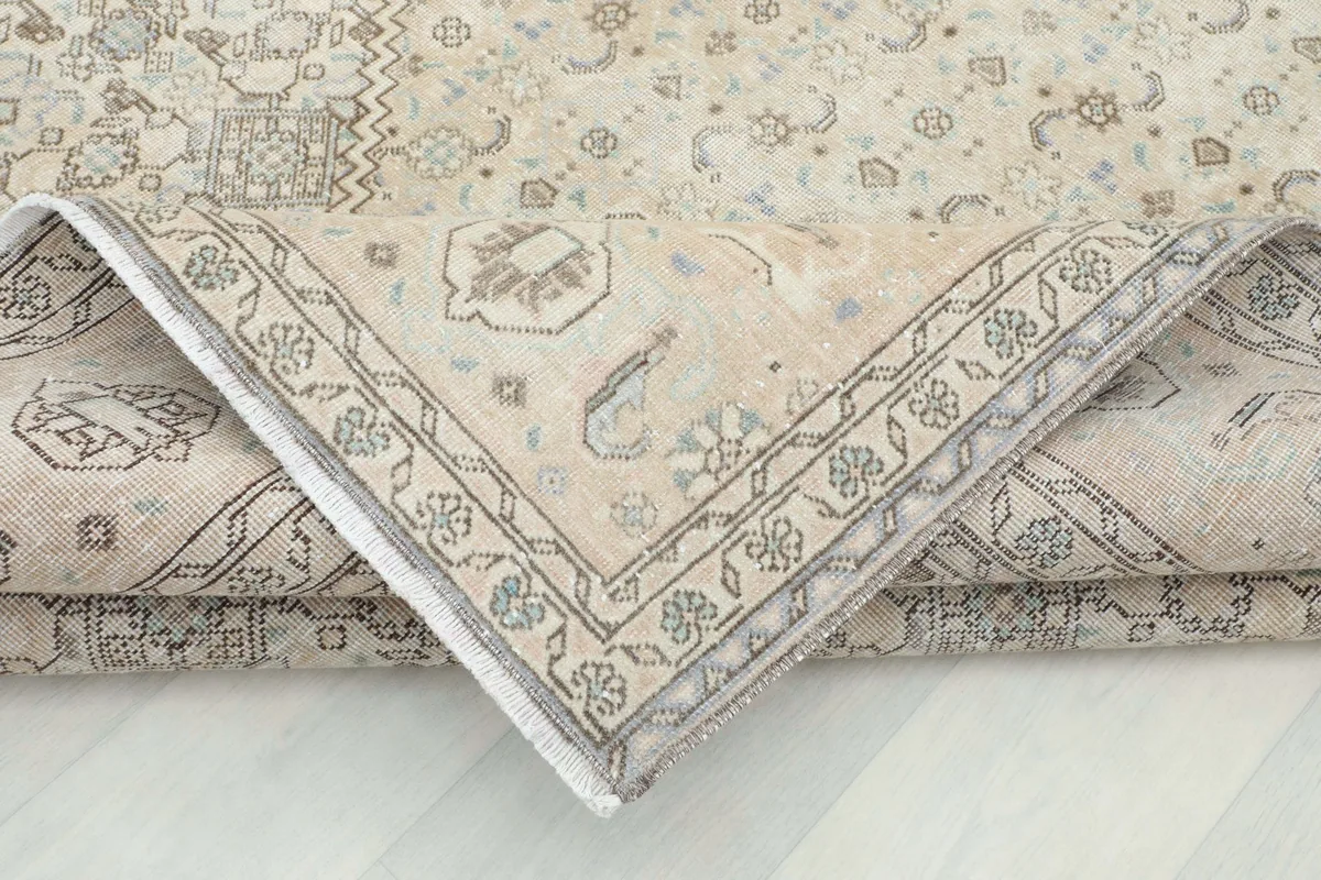 Corner of the rug folded over, revealing the back of the hand-knotted wool on cotton foundation.