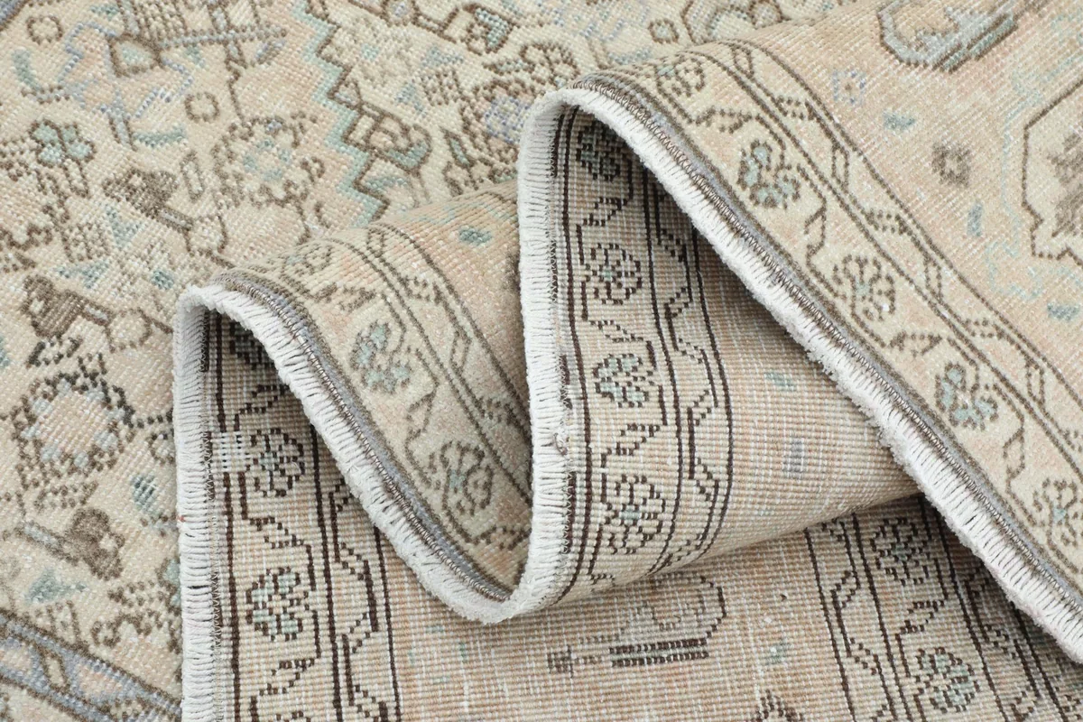 Rug rolled up partially, showing the flexibility and thickness of the vintage hand-knotted construction.