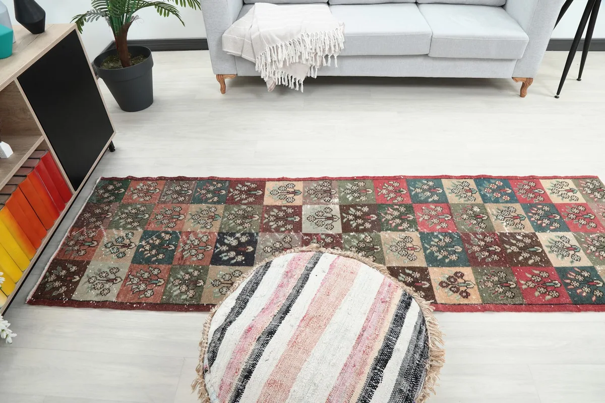 Runner rug in a living room, viewed from above a striped ottoman towards a sofa