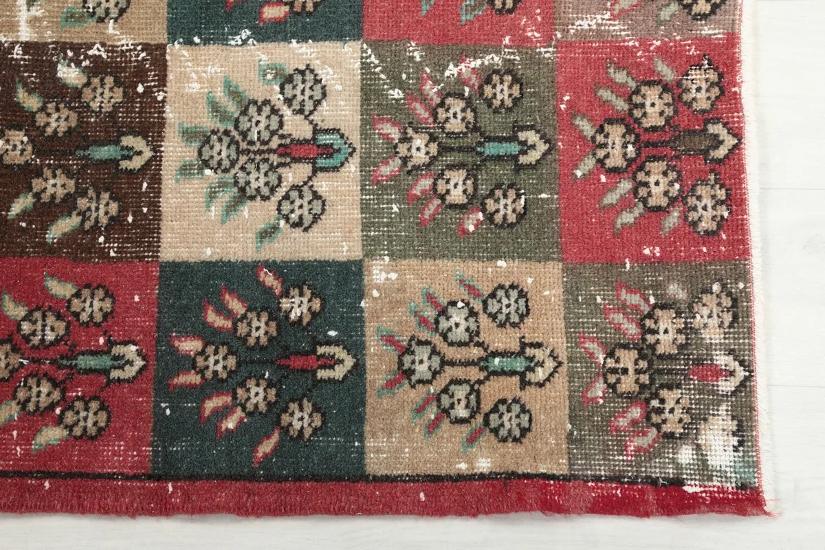 Detailed view of the rug's surface, highlighting red, teal, and beige squares with floral patterns