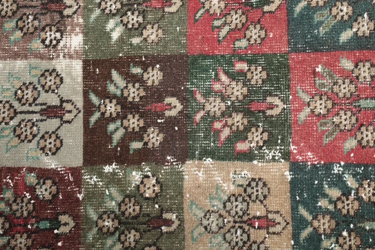 Close-up of individual squares, revealing green, brown, and red tones with motifs and patina