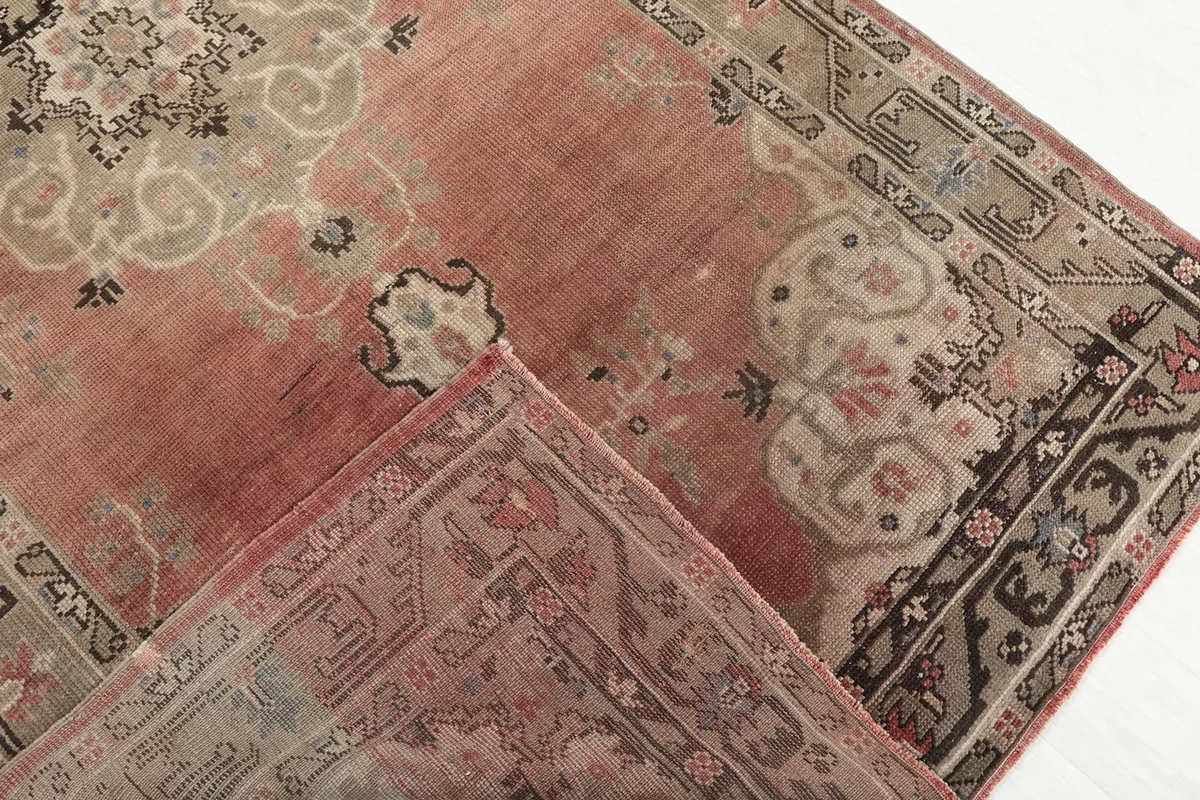 Folded corner revealing the wool pile and cotton foundation of the vintage rug