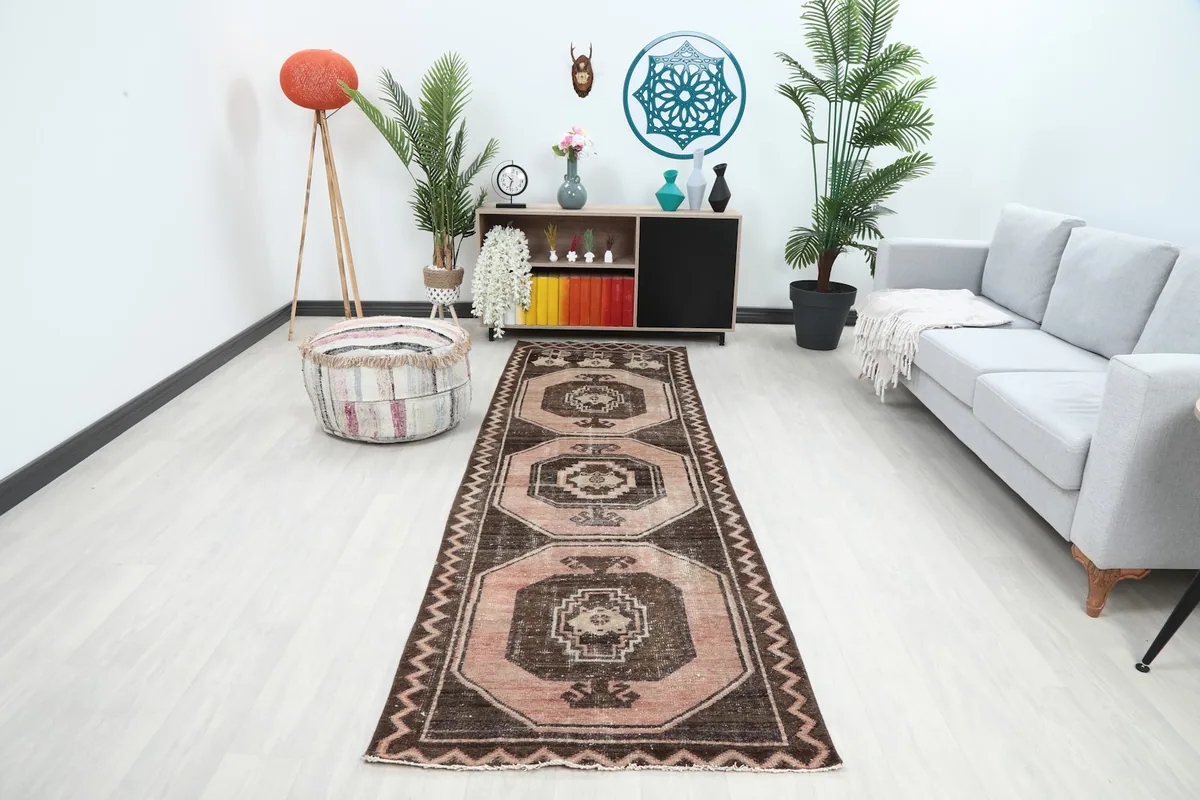 Vintage runner rug displaying rose and brown geometric patterns in a modern hallway setting