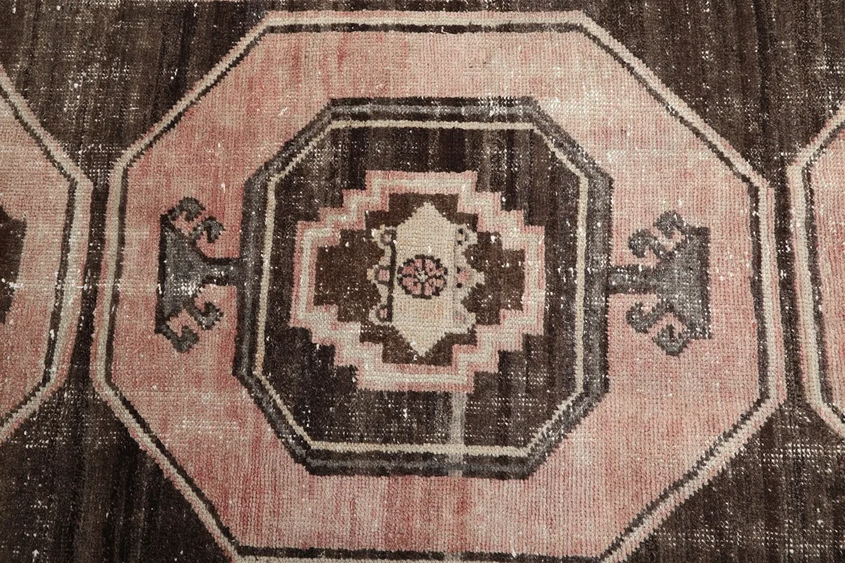 Close-up of a single geometric medallion with tribal motifs in rose, brown, and cream