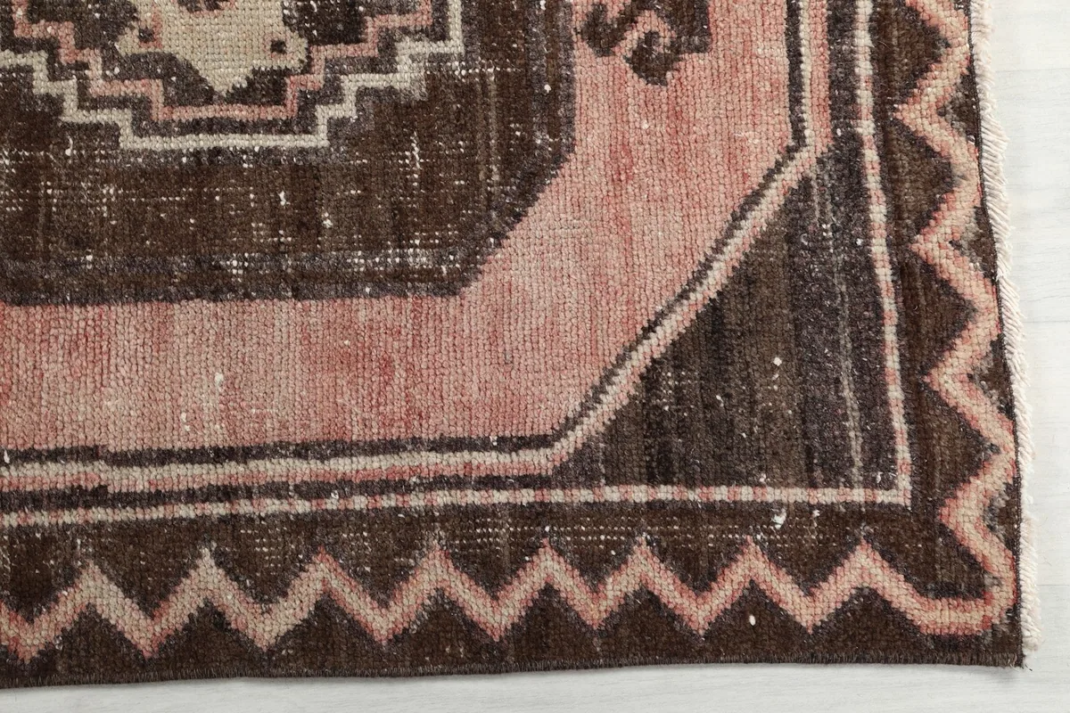Detail of the zigzag border and faded rose tones on the vintage Anatolian runner rug