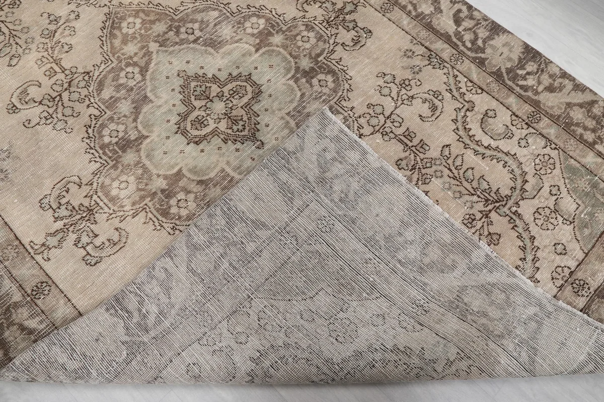 Corner of the rug folded back to reveal the cotton foundation and hand-knotted backing