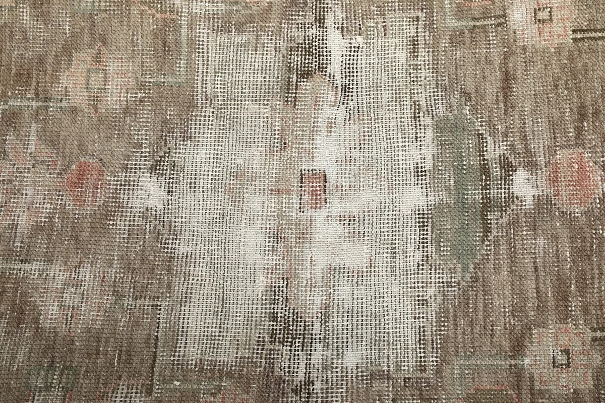 Close-up of the low wool pile texture and visible patina in the center of the rug