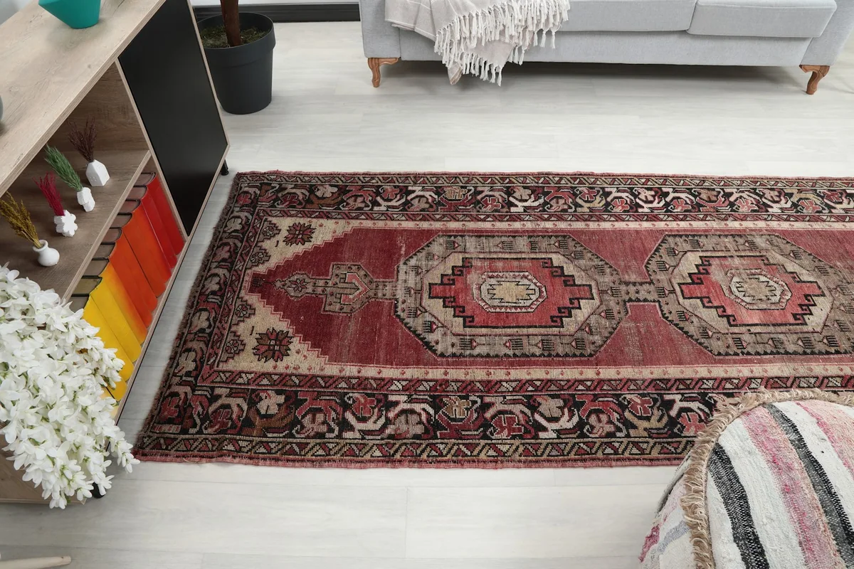 View of the runner rug extending into a living space, with a striped ottoman and bookshelf visible.