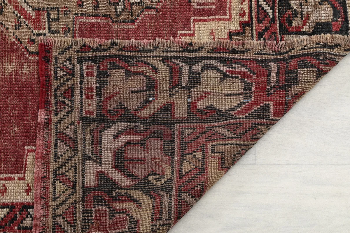 View of the back of the rug and a corner, showing the hand-knotted construction and fringe.
