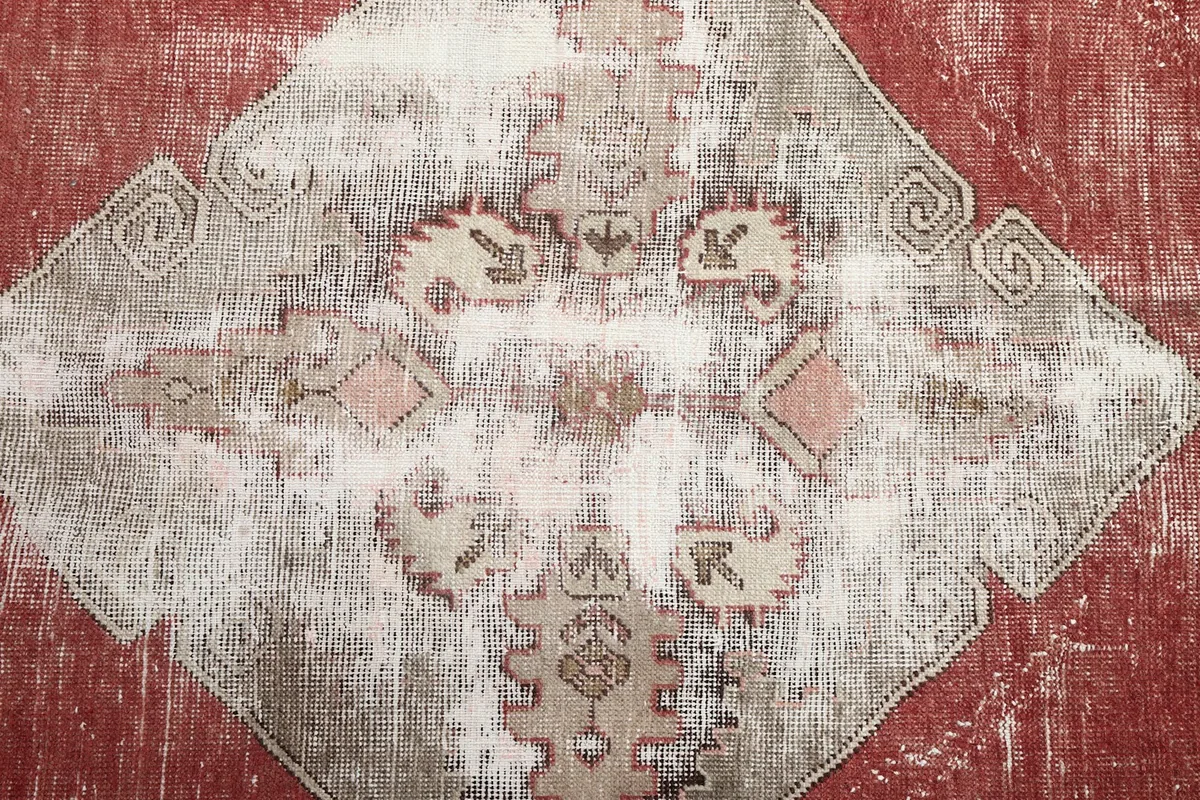 Detailed view of a gray geometric medallion, highlighting the hand-knotted texture and patterns.