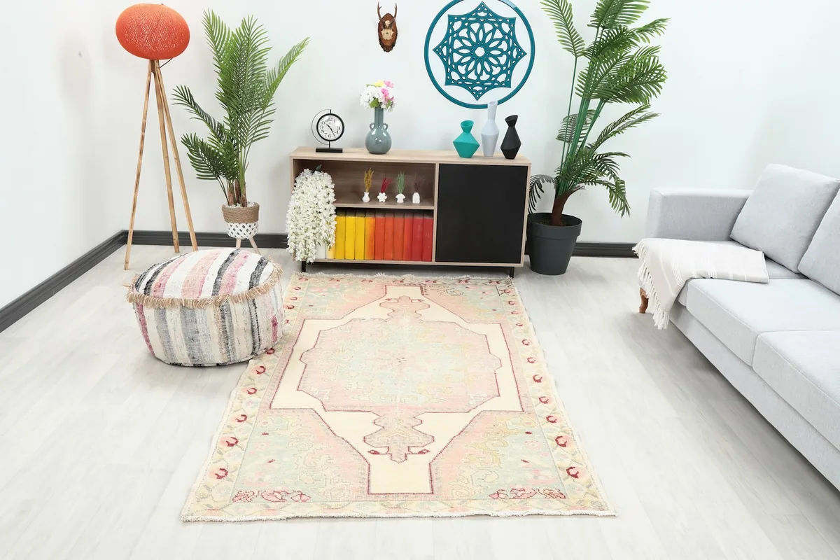 Vintage pink and cream rug in a modern living room setting with a light sofa and pouf