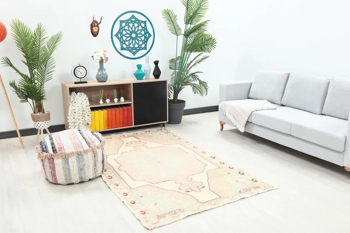 Area rug from an angle in a living space, highlighting its faded pink and green tones