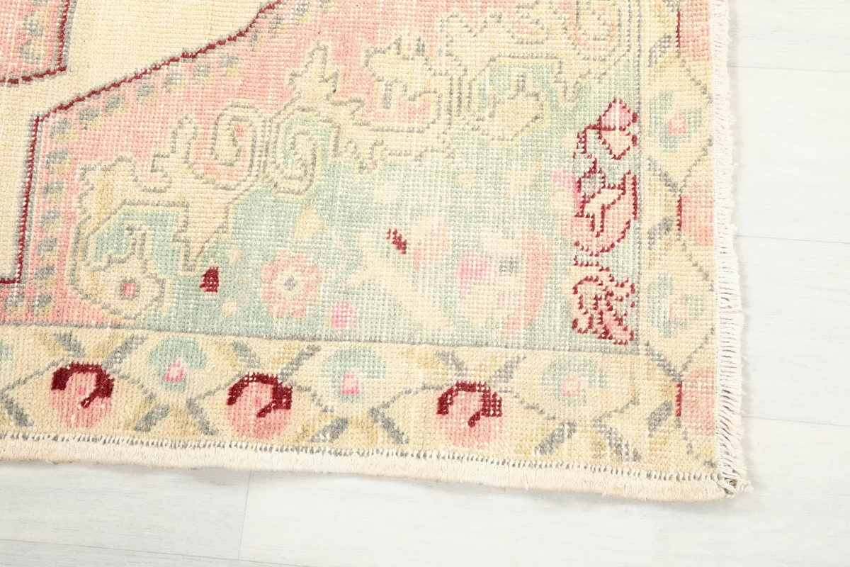 Detailed view of the rug's border with small stylized red and pink floral motifs