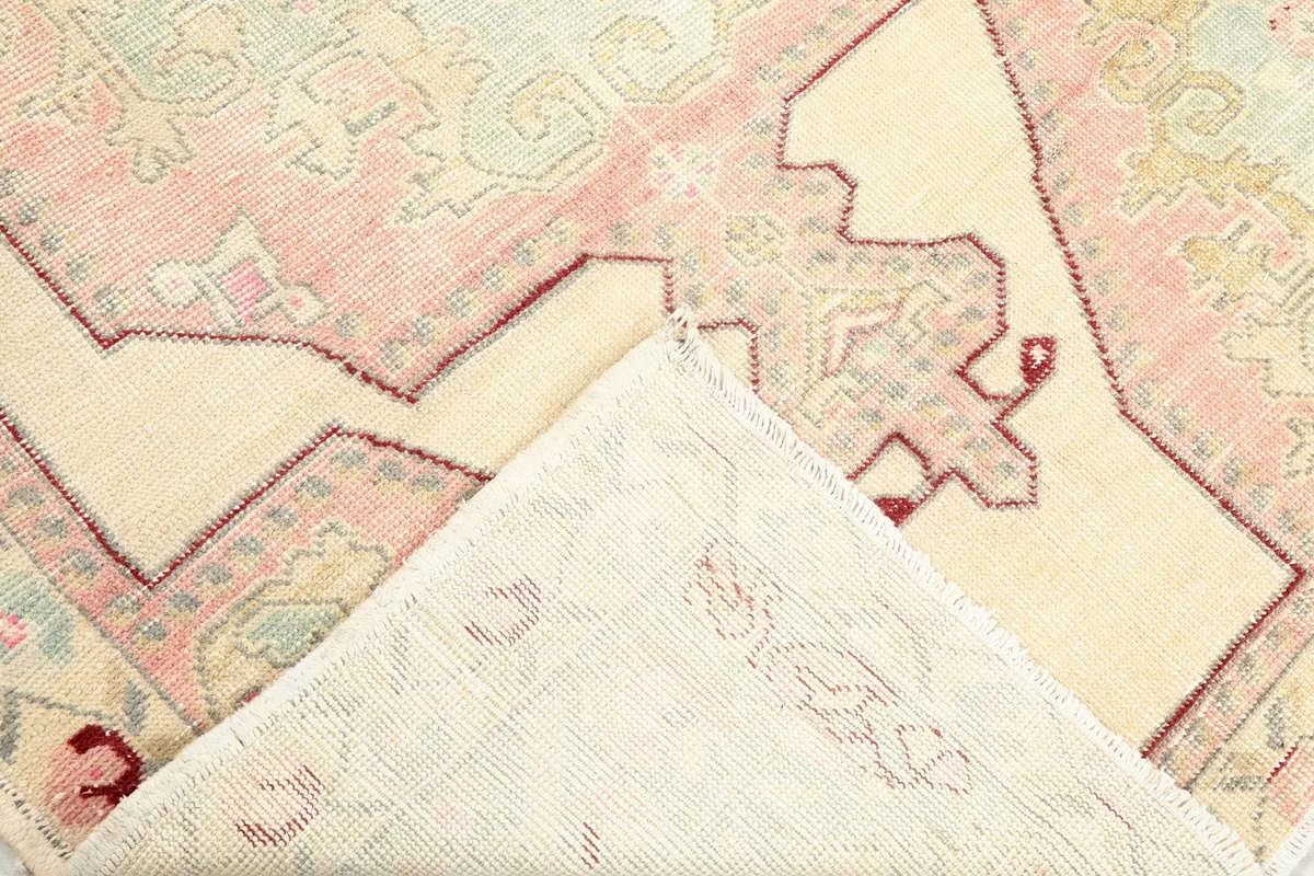 Corner of the rug folded back, revealing the hand-knotted cotton foundation