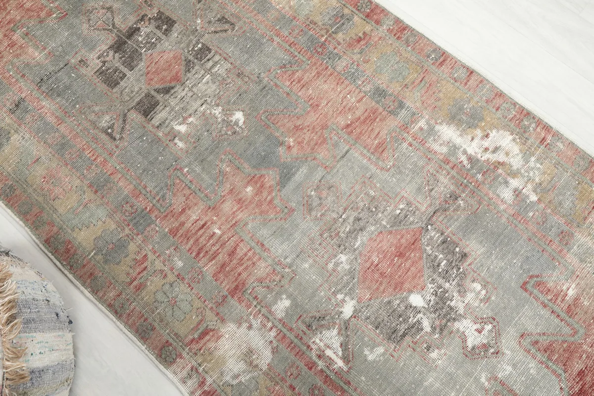 Overhead detail of the rug's central design, highlighting wear and the interplay of rust and gray colors.