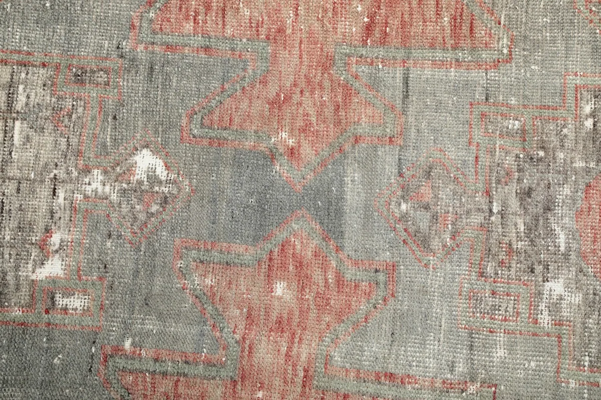 Close-up of the low wool pile, showing the hand-knotted texture and distressed areas of the rug.