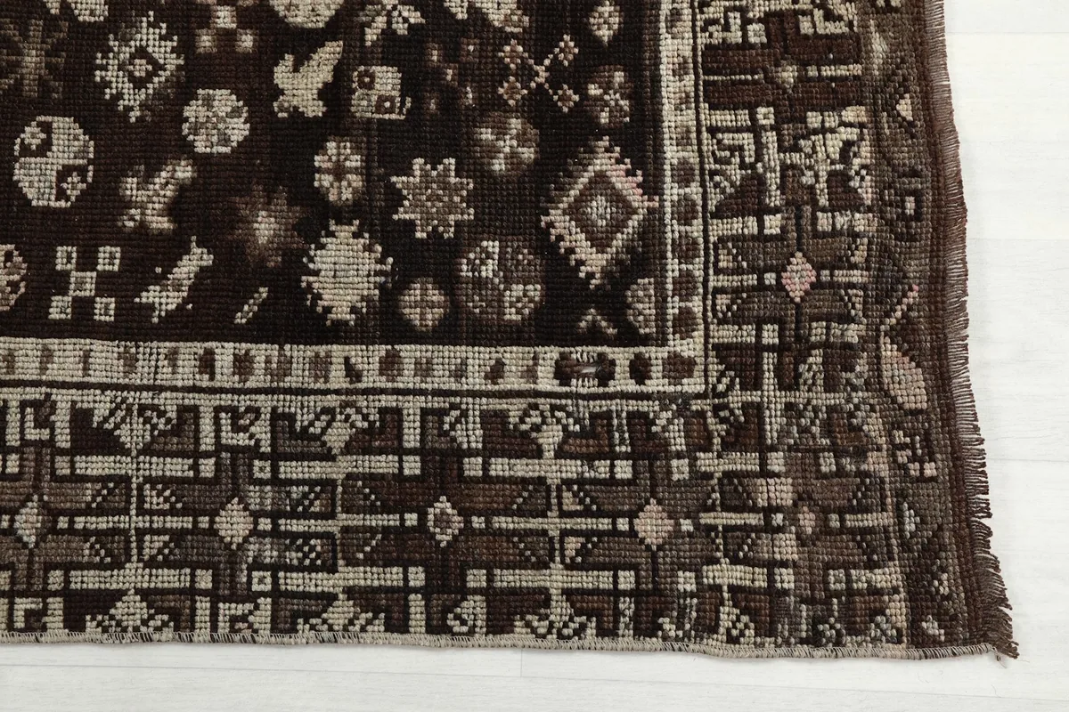 Detailed view of the rug's border and field, showcasing the beige geometric patterns on brown.
