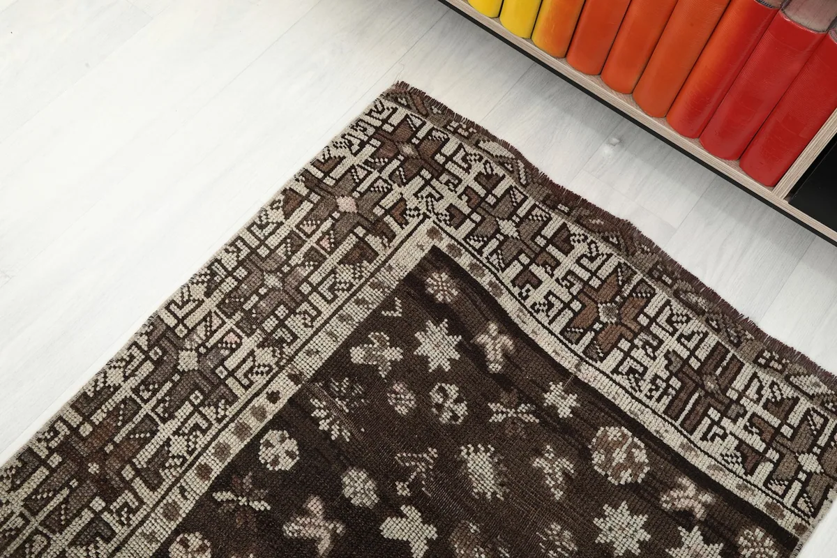 Corner detail of the runner rug, showing the intricate beige and brown border design.
