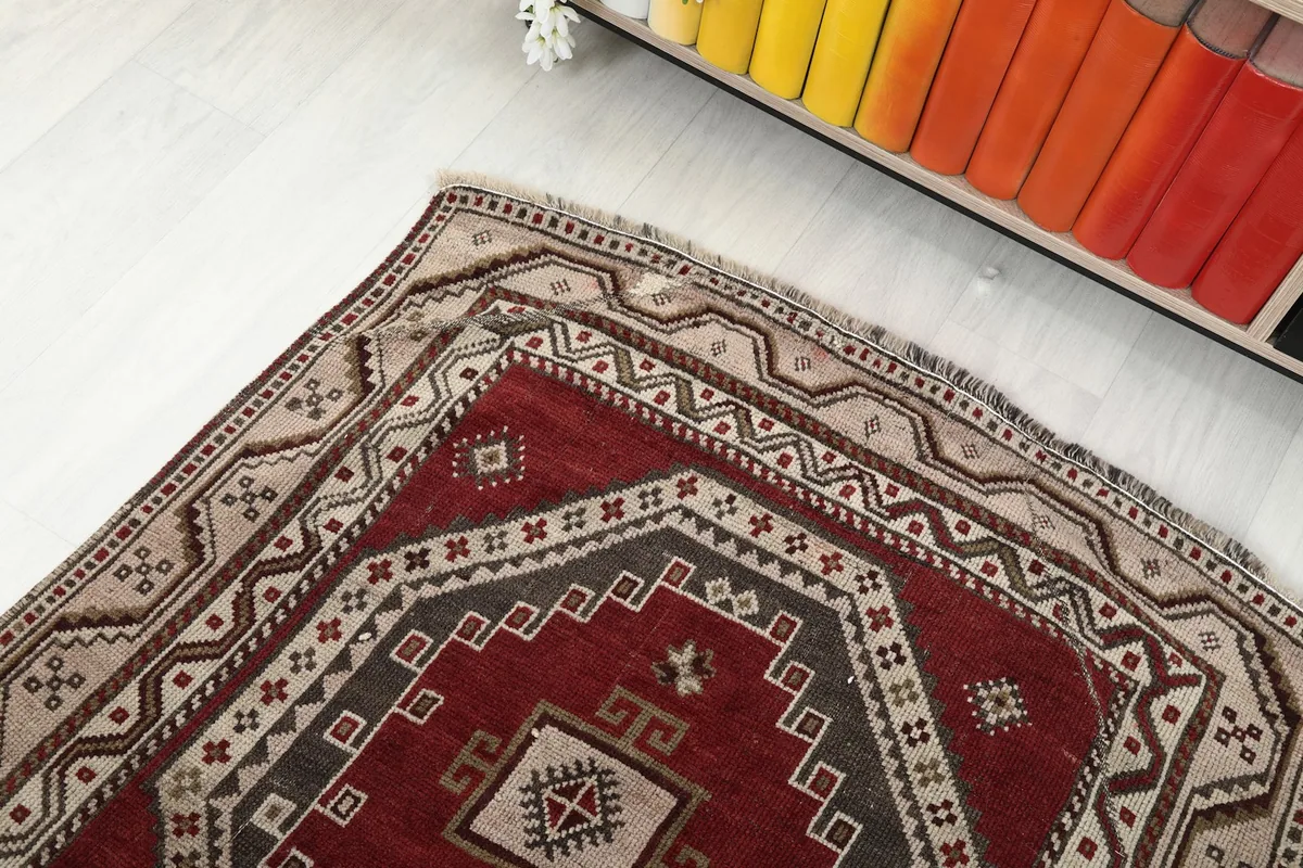 Angled view of the rug's end, showing the border design and a glimpse of the shelf with colorful books.