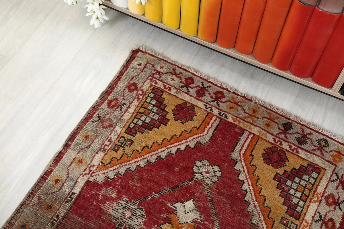 Upper corner of the rug showing red field, yellow geometric patterns, and beige border