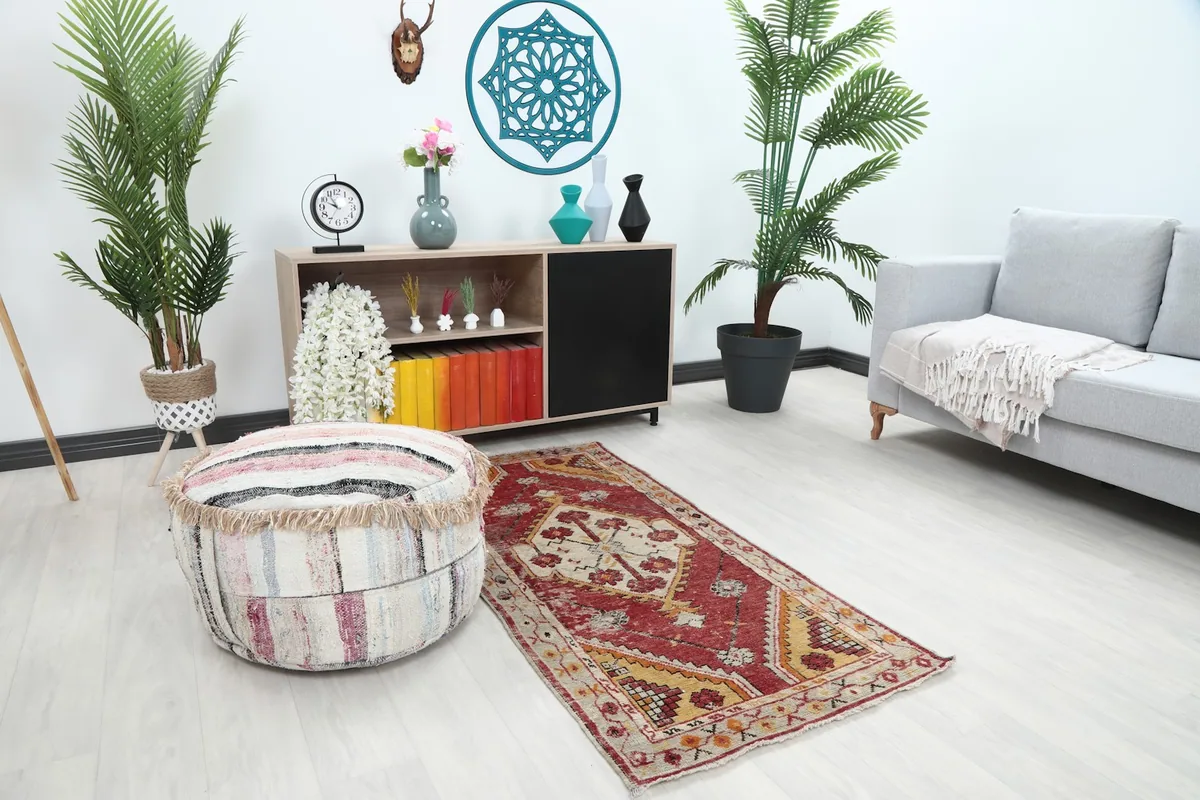 Angle view of the small Anatolian rug in a home decor setting with a striped ottoman