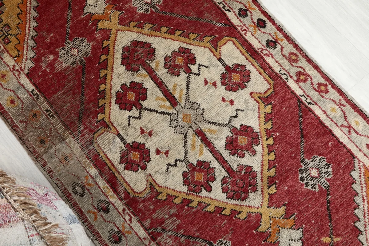 Close-up of the central cream medallion with red floral-like motifs and yellow accents