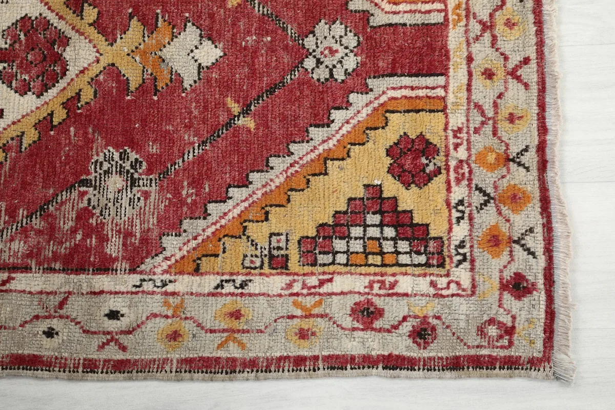 Detail of the rug's beige border and corner showing geometric patterns and fringe