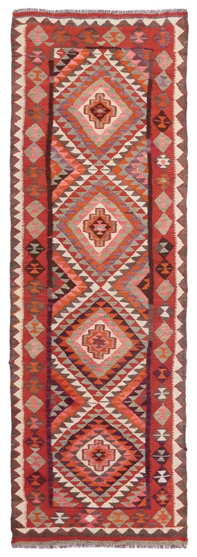 Top-down view of a vintage Anatolian runner rug with red, orange, gray, and brown geometric patterns