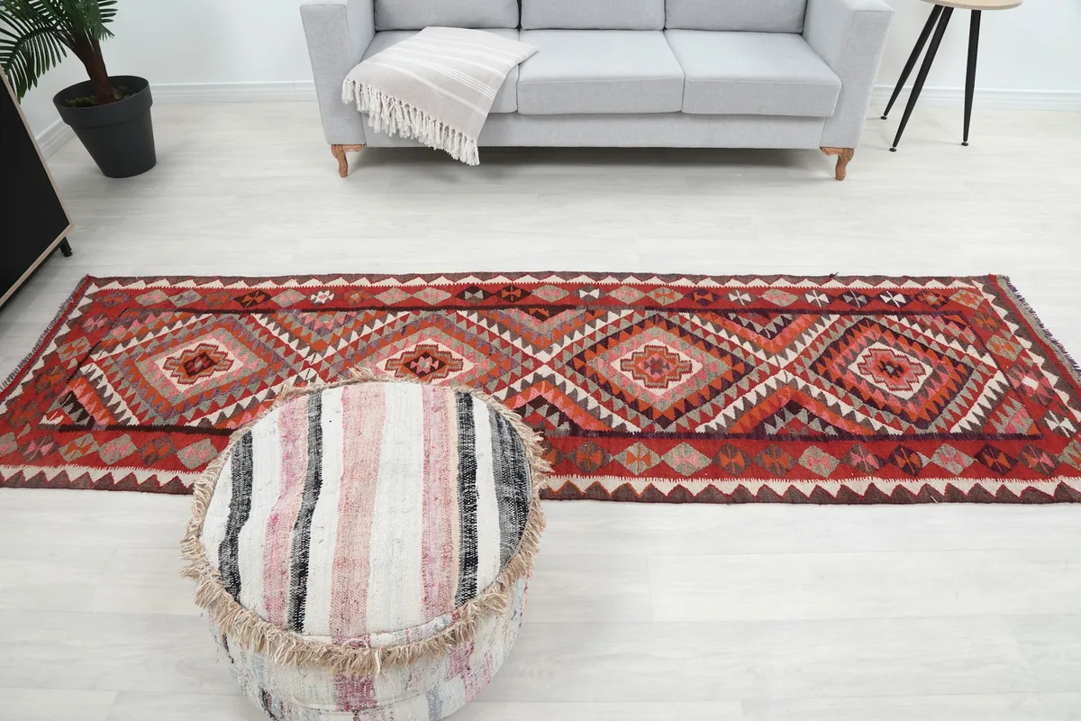 Full length view of the red geometric runner rug in a room with a gray couch and decorative ottoman