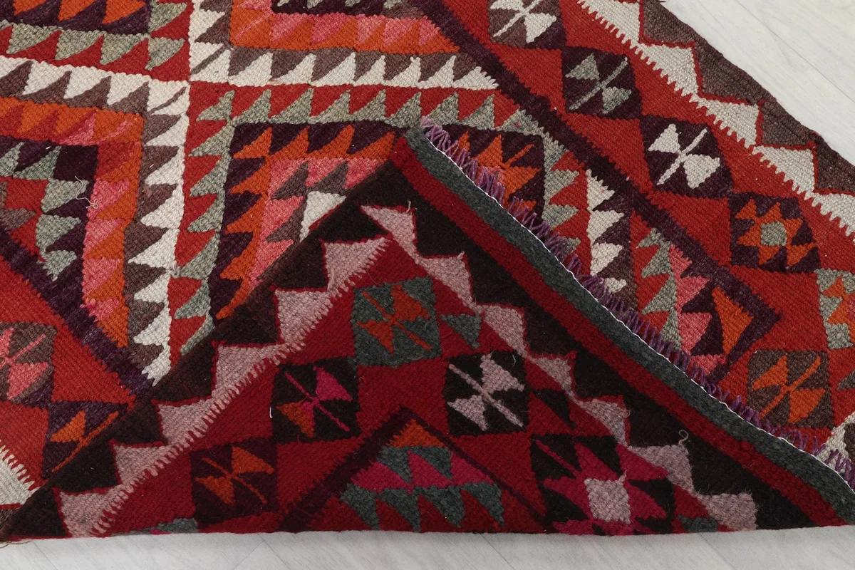 Folded corner of the rug revealing the cotton foundation and the reverse side of the hand-knotted pattern