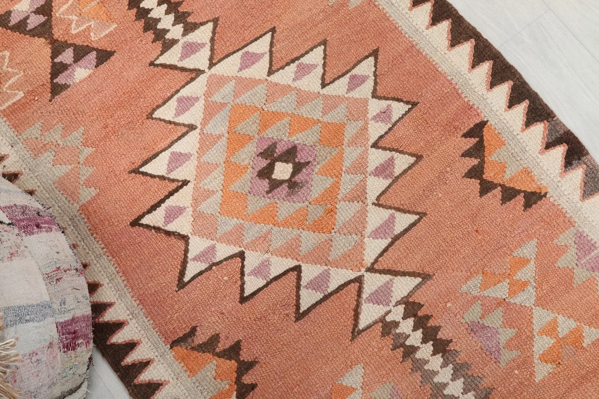 Close-up of the central geometric medallion motif in orange, ivory, purple, and brown tones