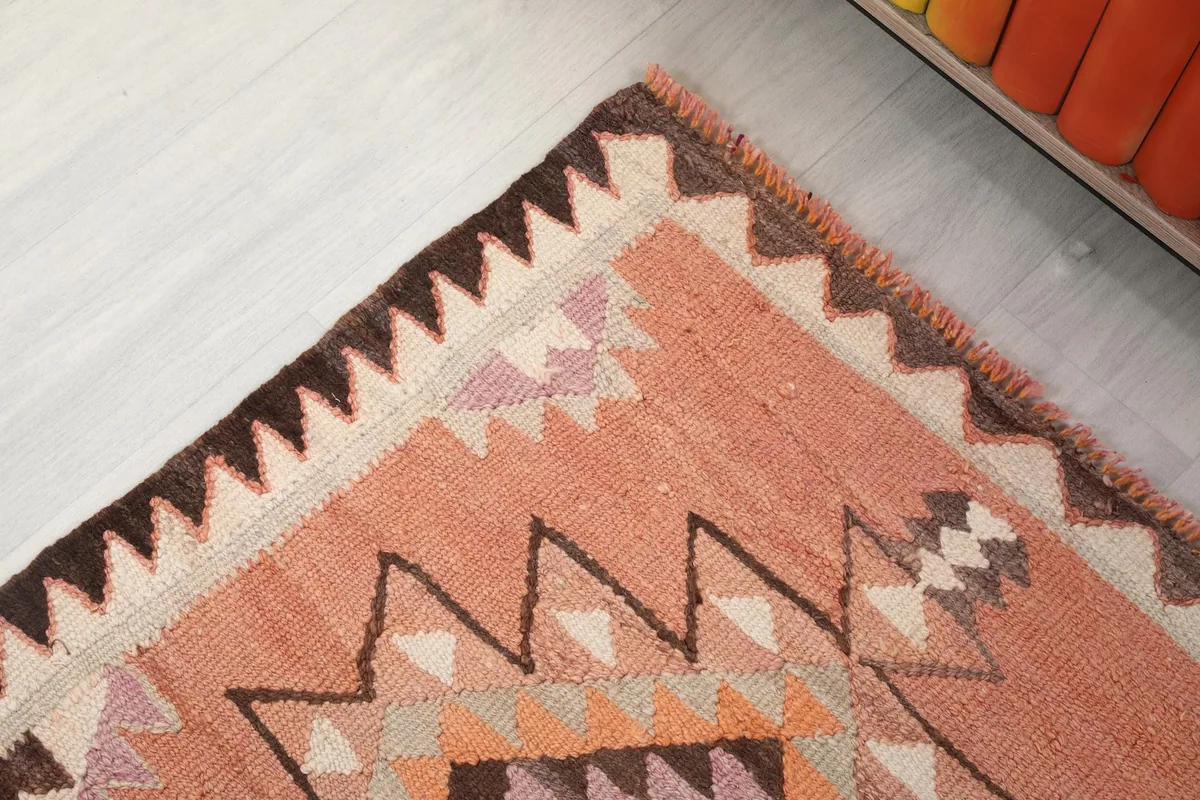 Detail of the brown and ivory sawtooth border design along the edge of the runner