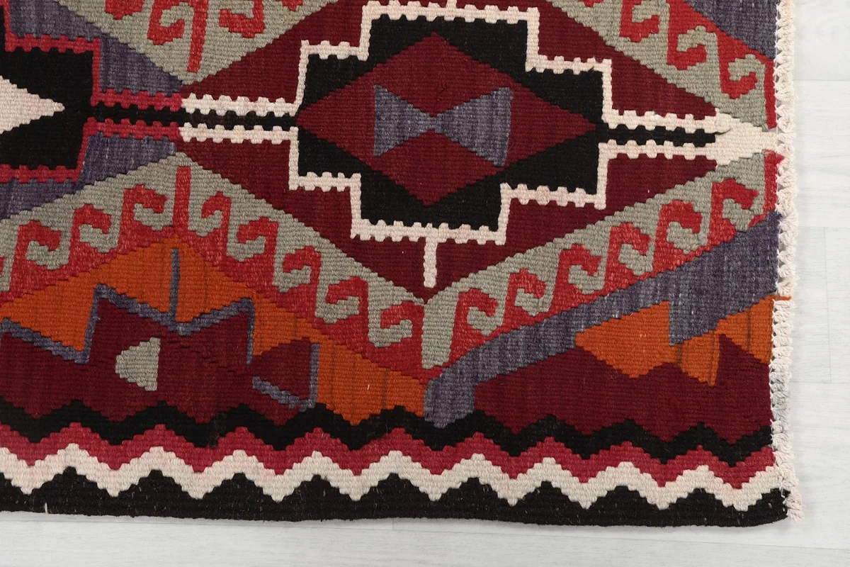 Detailed view of the red, black, and ivory geometric motifs and border design
