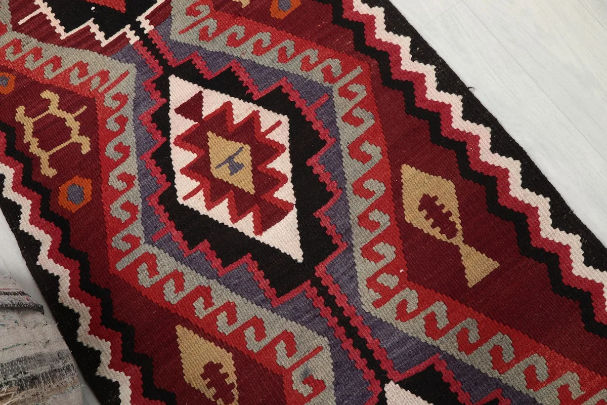 Close-up of the central geometric medallion and tribal elements in red and gold