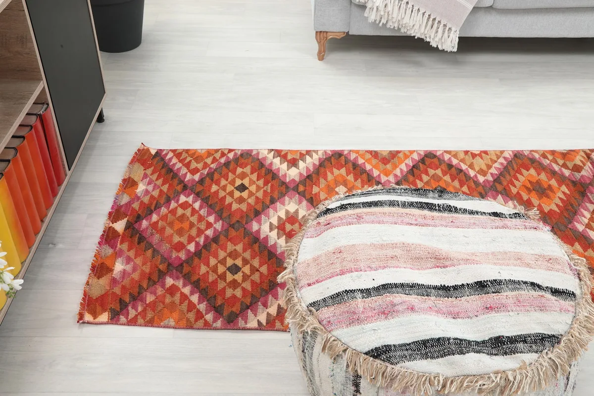 View of the runner rug stretching across a room, with an ottoman in the foreground