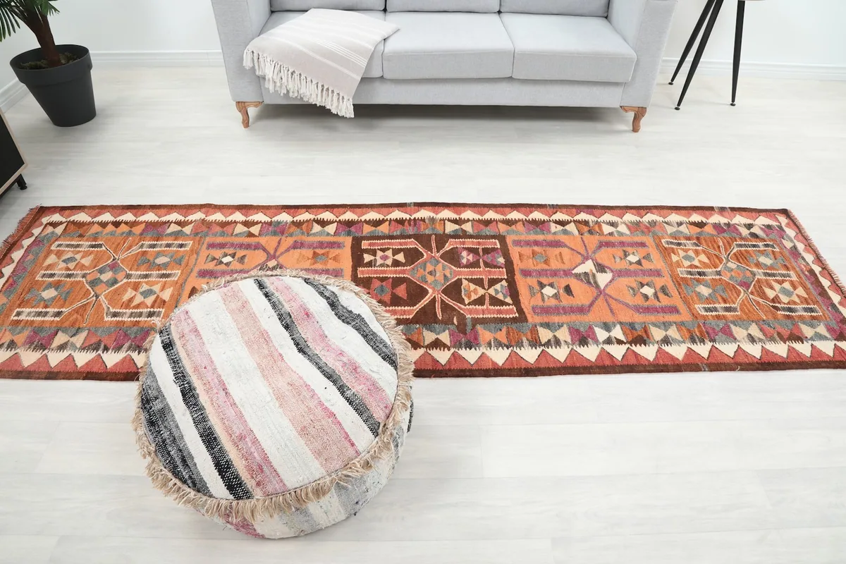 Full length view of the runner rug in a room with a sofa and pouf