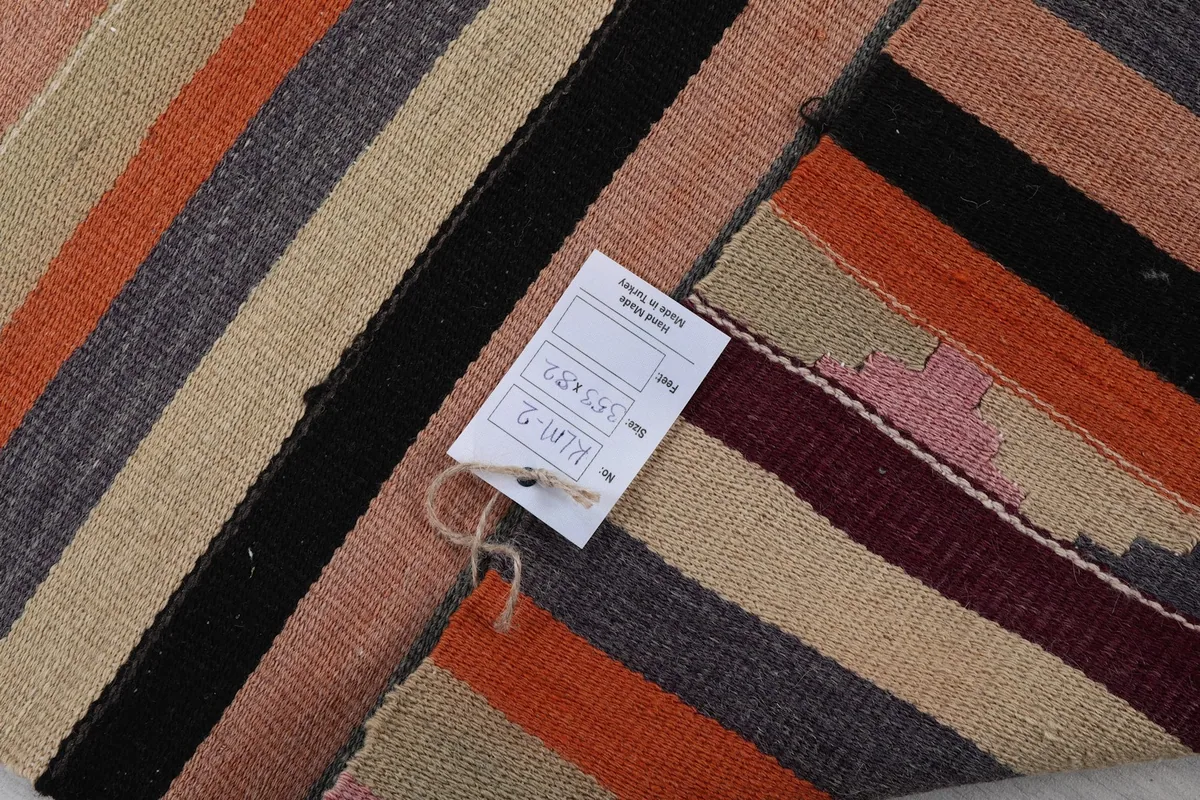 Detail of the rug's back with a product tag, showing the reverse side's weave and colors.